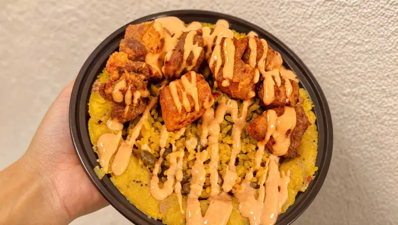 Mofongo bowl topped with chicharrones de pollo and a drizzle of mayoketchup